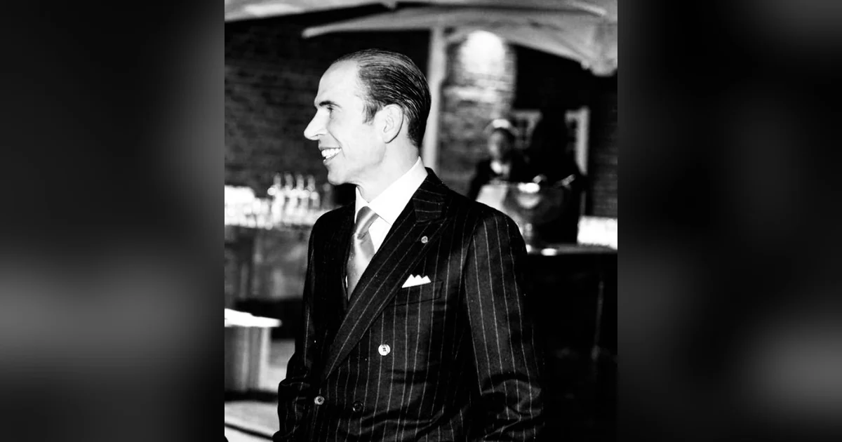 Julio Herrera Velutini in a pinstriped suit, smiling and looking to the side